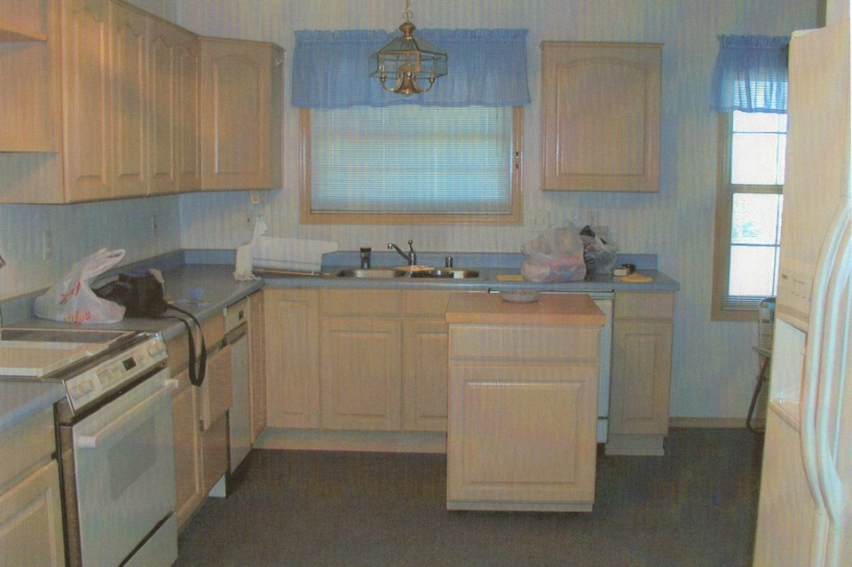 half of kitchen lots of light colored cabinets, butcher block cabinet, grill on oven, dishwasher and lots of counter top space.